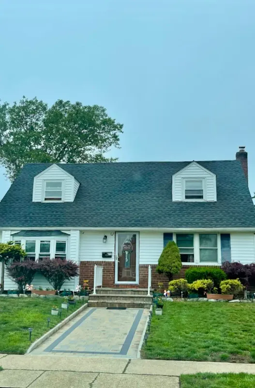 Cape Cod home with a new dark shingle roof and dormer windows