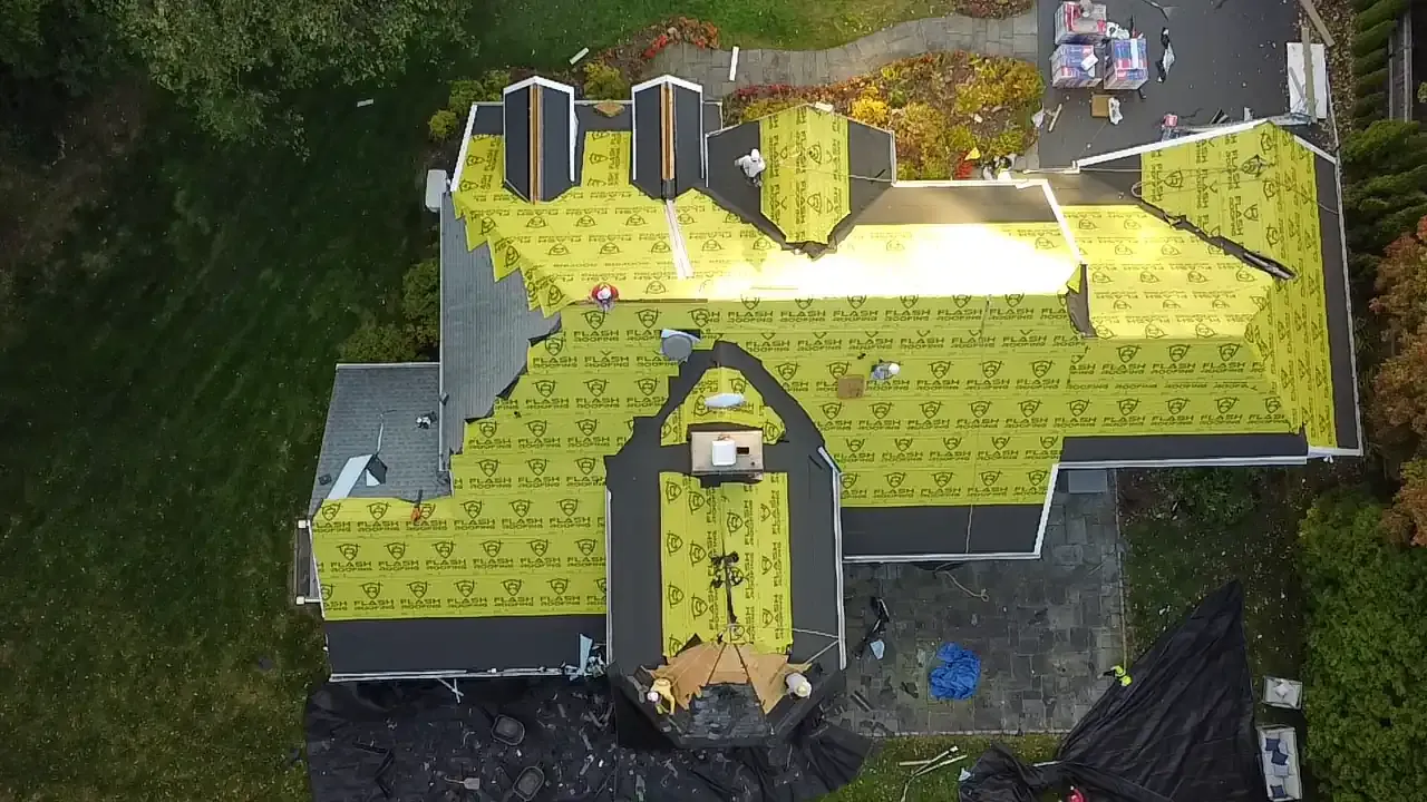 Roof replacement in progress with yellow FLASH synthetic underlayment